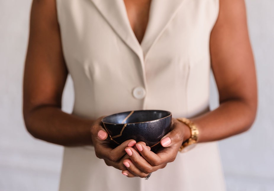 Hands holding a navy kintsugi bowl with gold repair lines